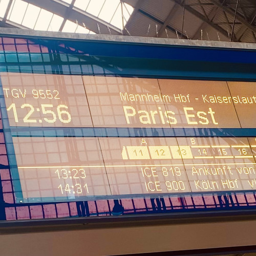 KI generiert: Das Bild zeigt eine Anzeigetafel in einem Bahnhof, die den Zug TGV 9552 nach "Paris Est" mit Abfahrtszeit 12:56 Uhr anzeigt. Der Zug fährt über Mannheim Hauptbahnhof und Kaiserslautern.